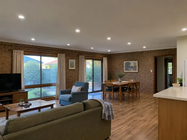 Living and dining room with recessed ceiling downlights, brick walls and timber floors in Box Hill
