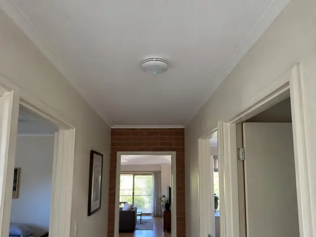 Hallway ceiling with a smoke alarm above doorways in a brick-and-plaster home in The Ponds